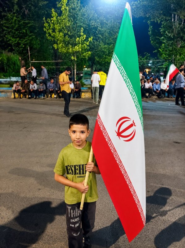 فردای ایران در دستان کوچکش؛ پسری با پرچم، در شبِ همدلی · کودکانه اما استوار؛ نسل آینده، پاسدار امروز · آن پرچم در آن دست کوچک، بزرگ‌ترین پیام امید